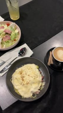 Siyah bir masada iki kişilik romantik bir akşam yemeği, makarna, Sezar salatası, kahve kapuçino ve limonata, sarı restoran, kafe yemeği, öğle yemeği, öğle yemeği, öğle yemeği, çift, randevu. Yüksek kua