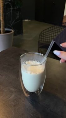 Masadaki protein içeceği bir cam bardakta duruyor. Yanında da sütlü süt tozu ve laktoz restoranı kahvesi var. Siyah bir masa. Yüksek kalite 4k görüntü