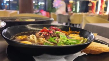 Japon baharatlı ramen şehriye çorbası, ramen çorbası, erişte, udon yumurtaları, yeşil soğan, soya sosu, siyah tabakta, lüks Asya mutfağı miso çorbası sunumu.