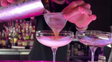 Barmen zenciye alkol dökerek barda kokteyl hazırlıyor. 6K kamerayla yakın çekim.