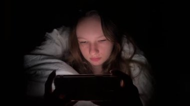 Genç Çekici Bir Kadının Gece Yatağında Akıllı Telefondan Oyun Oynayan Portresi. Yüksek kaliteli 4K televizyon dizisi 