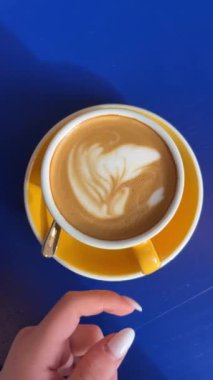Kahve dükkanındaki mavi bir masada sütlü latte cappuccino yassı beyaz standı sabah kahvaltısı kafeteryasının etrafına döküyor. Yüksek kalite 4k görüntü