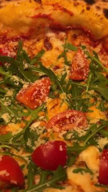 Kız bir dilim pizza peyniriyle margherita 'yı roka, domates dilimi ve peynirle birlikte aşçılık malzemeleriyle donatıyor. Yüksek kalite 4k görüntü