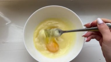 Yumurtaları karıştırıcı ile karıştırıyorum, yakın plan. Ev mutfağında yemek pişirmek. Tavuk yumurtalarını karıştırıcıyla çırpmak. Yüksek kalite 4k görüntü