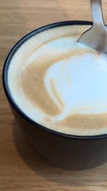 Kaşık ile çok iştah açıcı kahve köpüğü hemen beyaz fincanda karıştırın müzik için ekran koruyucusu siyah tabut kapuçino kapuçino kapuçino frappesi ile sütlü latte kahve için
