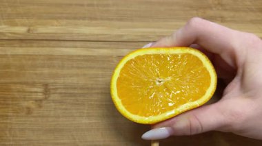 Taze portakalı sıkıyorum. Portakal suyu sıkan birinin resmi. Portakal ezme makinesine yarım portakal sıkmak. Taze çiğ narenciye tutarken. Yüksek kalite 4k