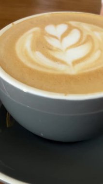 Kız eli kahve içer. Cappuccino 'yu ahşap masada tutan kızı yakın plan çek. Sabah kahvaltısı ve kahve arkaplanı. - Evet. Yüksek kalite 4k görüntü