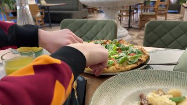 Ahşap masada parmesan peynirli leziz pizza Sezar 'ı sos dökerken. Bitkisel pizza. Marul, domates, peynir.