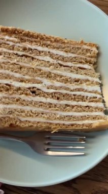 Napolyon keki, kahve dükkanındaki yeşil pastel bir tabağın üzerinde. Koyu kahverengi bir masa. Lezzetli klasik girdap şekeri. Yüksek kalite 4k görüntü