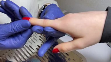 Mavi eldivenli masaj. Manikür. Yeni yapılmış kırmızı tırnaklı güzellik salonu.