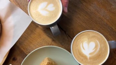 Tahta bir masa üzerinde güzel bir kahvaltı kahve ve kekler kruvasan sabah el hareket ettirme fincan garsonu kahve aromatik tatlı kek getiriyor latte cappuccino Düz Beyaz. Yüksek kalite 4k