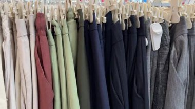 Askılarda çeşitli renklerde bir sürü kıyafet var. Mağazada çeşitli kadın kıyafetleri var. Elbiseler, ceketler, gömlekler, etekler ve diğer kıyafetlerden oluşan bir panorama. Yüksek kalite 4k görüntü