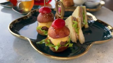 Lokantada bir tepsi lezzetli sığır eti sunulurken erkek bir müşteri yemek için hamur işi alıyor. Sandviç, mini burger.