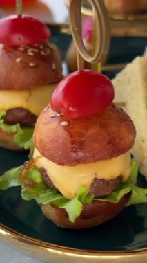 Lokantada bir tepsi lezzetli sığır eti sunulurken erkek bir müşteri yemek için hamur işi alıyor. Sandviç, mini burger.