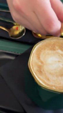 Kahve dükkanının kapuçino kapuçinosundaki yeşil kupa Düz beyaz el kaydırmalı kahve restoranı kafeteryası kafein dopamin içiyor. Yüksek kalite 4k görüntü