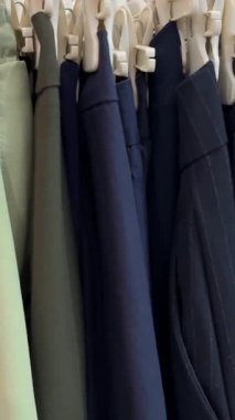 Askılarda çeşitli renklerde bir sürü kıyafet var. Mağazada çeşitli kadın kıyafetleri var. Elbiseler, ceketler, gömlekler, etekler ve diğer kıyafetlerden oluşan bir panorama. Yüksek kalite 4k görüntü