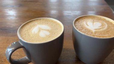 Bir fincan kahve cappuccino ve kahve tablosu, en iyi manzara. Latte sanat kahvesi masada içilmeye hazır. Sabah kahvesi aromalı kapuçino. Yüksek kalite 4k görüntü