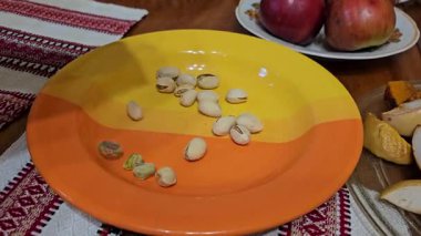 Çatlamış kabuklu kurumuş fıstık ve yeşil çekirdekler bir tabağa düşüyor. Yüksek kalite 4k görüntü