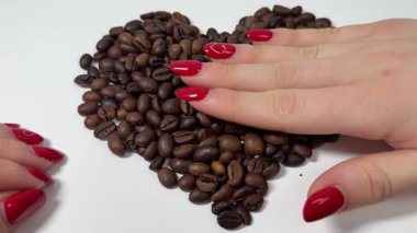 kalp, beyaz arka planda kahve çekirdeklerinden yapılmış eller kalp kafeini içeceği oluşturur..