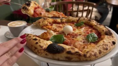 Yeşil ojeli kadın eli, salam ve pastırma ile lezzetli bir pizzayı kesiyor. Arka planda Sezar salatası ve kahve tamamlandı. Pizza mozzarella fesleğeni, pizza kahveli eller.