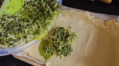 Ev sahibesi turta için dolguları karıştırıyor. Peynirli turta yapmak için peynirli ıspanak. Ispanaklı turta pişirme işlemini adım adım yoğur