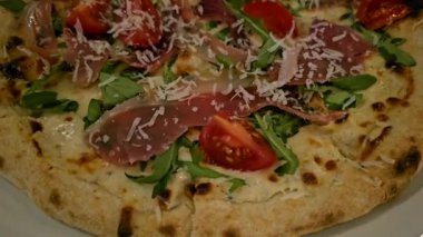 Eritilmiş mozzarella peynirli taze İtalyan pizzası, domuz pastırması jambonu ve roka yaprakları beyaz masadaki tabakta. Yüksek kalite 4k görüntü