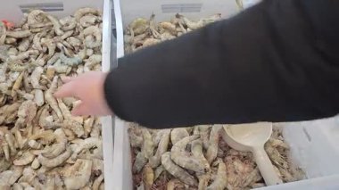 Alıcı markette çantaya karides koyar. Buzdolabını aç.