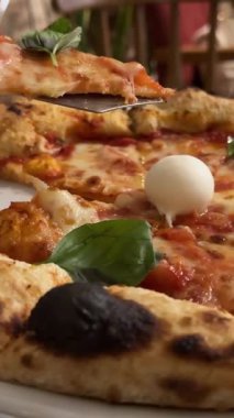 Yeşil ojeli kadın eli, salam ve pastırma ile lezzetli bir pizzayı kesiyor. Arka planda Sezar salatası ve kahve tamamlandı. Pizza mozzarella fesleğeni, pizza kahveli eller.