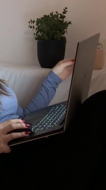 Genç bir kız, yatakta kanepede oturuyor ve kulaklıkla dizüstü bilgisayarla film seyrediyor TV dizisi izliyor müzik mesajları teknolojisi dinliyor. Yüksek kalite 4k görüntü