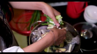 Yeşil soğan doğrayan Asyalı kadın elleri tahta tahtada Asyalı kadın gerçek hayatta evde yemek pişiriyor. Yüksek kaliteli FullHD görüntüler