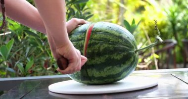 Masada bıçakla karpuzu ikiye bölmek. Taze yaz meyvesi. Kapatın. Yüksek kaliteli FullHD görüntüler