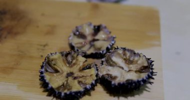 Gastronomi. Şef mutfak bıçağıyla deniz kestanesi kabuğunu kırıyor.. 