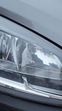 Bir adam gri bir arabanın farına bir bez parçası siler. Yüksek kalite 4k görüntü