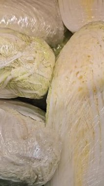 Plastiğe sarılmış Çin lahanası. Süpermarkette ya da sebze pazarında satılık lahana. Sebzeler. Marketteki ürünler. Dükkandaki rafta duran Çin lahanasının yakın çekimi..