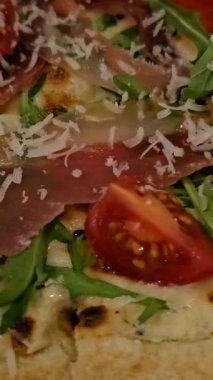 Eritilmiş mozzarella peynirli taze İtalyan pizzası, domuz pastırması jambonu ve roka yaprakları beyaz masadaki tabakta. Yüksek kalite 4k görüntü