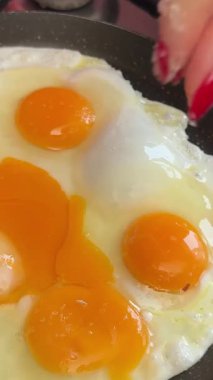 Kızartma tavasında yumurta tuzlayan kadınlar güler yüzlü dört yumurta sarısı.