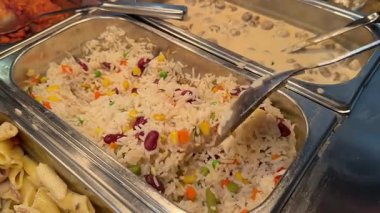 Açık büfedeki tavuklu pilav ve lezzetli salatadan dökülen pirinç ve sebze karışımı. Yakın plan. Yüksek kalite 4k görüntü