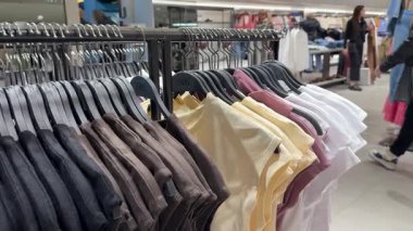 Bershka kadınları alışveriş merkezindeki giysi ürünlerine bakarlar. Çekici, mutlu bir kız mağazaya girip elbise ve elbise raflarından yeni tişört seçmeyi seviyor. Polonya Katowice 03.22.2025