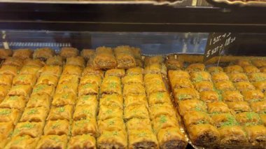 Bir dükkan vitrininde sergilenen, doğranmış fındık ve bal ile tatlandırılmış fileto katmanlarından yapılmış tatlı bir hamur işi olan baklavaya yakın durun. Yüksek kalite 4k görüntü