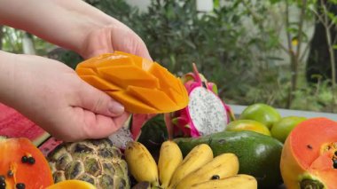 Taze mango ve dilimlenmiş parçaları ahşap bir masada, canlı tropikal meyveler sergiliyor. Mutfak ve sağlıklı yaşam tarzları için mükemmel. Yüksek kalite 4k görüntü