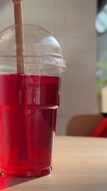 Açık büfede pipetle plastik bir fincanda kırmızı meyve suyu ya da komposto, alışveriş merkezinin penceresinden güneşli hava. Yüksek kalite 4k görüntü
