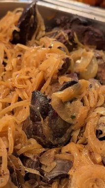 Şef doğu yemeği servis ediyor, karamelli kırmızı soğanı kızarmış ciğere patates dilimleriyle koyuyor. Yakın plan. Yüksek kalite 4k görüntü