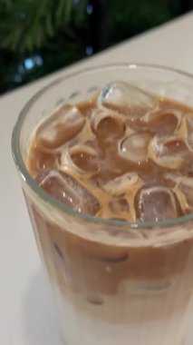 Ağır çekimde ve buzlu Americano kahvesini bardakta döndürüyor. Yüksek kalite 4k görüntü