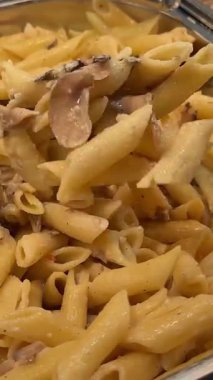 Bir yemek organizasyonunda tavada servis edilen bezelyeli, bol soslu canlı makarna. Mutfak, etkinlik planlama ya da gıda endüstrisi projeleri için ideal. Yüksek kalite 4k görüntü