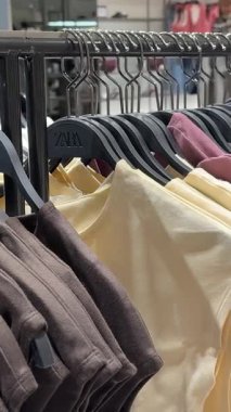 Bershka kadınları alışveriş merkezindeki giysi ürünlerine bakarlar. Çekici, mutlu bir kız mağazaya girip elbise ve elbise raflarından yeni tişört seçmeyi seviyor. Polonya Katowice 03.22.2025