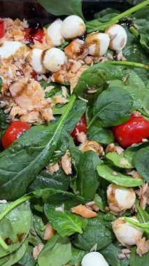 Domatesli mini mozzarella topu, roka, ıspanak ve çırpılmış yeşillikler, daire şeklinde. Vejetaryen salatası, Turning. Seçici odaklanma. Yüksek kalite 4k görüntü