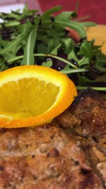 Tahta bir tahtanın üzerinde portakallı ve roka kaplı büyük bir biftek ve bir kaşıkla ketçap. Yüksek kalite 4k görüntü