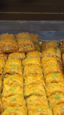 Bir dükkan vitrininde sergilenen, doğranmış fındık ve bal ile tatlandırılmış fileto katmanlarından yapılmış tatlı bir hamur işi olan baklavaya yakın durun. Yüksek kalite 4k görüntü