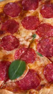 Şef lezzetli pizzanın üzerine taze fesleğen yaprağı koyuyor. Yanında da salam ve kabuklu pizza. Pizzacı mutfağında yeni pişirildi. Yüksek kalite 4k görüntü