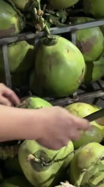 İnsan taze hindistan cevizi kırar, yeşil hindistan cevizi kabuğunu makineyle keser taze hindistan cevizi sütü içmek için, egzotik meyveler. Genç hindistan cevizleri sağlığını korumak için çalışır. Yüksek kalite 4k görüntü